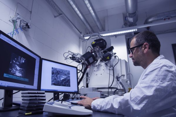 Lab assistant working with SEM image on computer